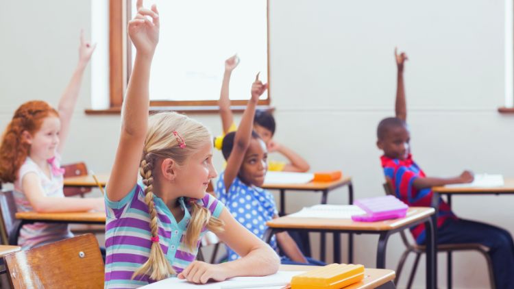 kids raising hands in a classroom